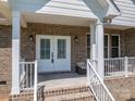 Inviting front porch features a brick facade, seating, and double door entry at 115 Woodward Way, Iron Station, NC 28080