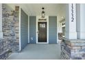 Inviting front porch with stone accents, modern lighting, and a craftsman-style door at 13332 Caite Ridge Rd, Davidson, NC 28036