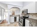 View of the kitchen with granite countertops, stainless appliances, and an archway to the living room at 13932 Queens Harbor Rd, Charlotte, NC 28278