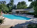 Community pool with lounge chairs and covered seating area surrounded by lush landscaping at 13932 Queens Harbor Rd, Charlotte, NC 28278