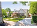 View of the home with long driveway, mature landscaping, brick exterior, chimney, and a detached garage at 2304 Commonwealth Ave, Charlotte, NC 28205