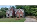 Beautiful two-story red brick home with a lush green lawn and a curved driveway at 3104 Highgate Dr, Fort Mill, SC 29715