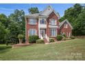 Beautiful two-story brick home with a manicured lawn, shuttered windows and lush, mature landscaping at 3104 Highgate Dr, Fort Mill, SC 29715