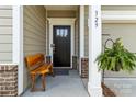 Inviting front entry with a black door, rustic wooden bench, and hanging plant at 329 Secretariat Dr, Iron Station, NC 28080
