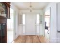 Bright foyer featuring hardwood floors, a classic chandelier, and a traditional, white front door at 4234 Woodglen Ln, Charlotte, NC 28226