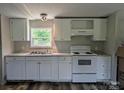 A well-lit kitchen features white cabinets, gray walls, modern appliances, and new wood-style vinyl flooring at 874 Old Home Place Way, Lincolnton, NC 28092