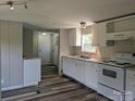 The kitchen features white cabinets, modern appliances, gray walls, and new wood-style vinyl flooring at 874 Old Home Place Way, Lincolnton, NC 28092