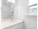 Clean and bright bathroom featuring a white vanity, large mirror, and a window that provides ample natural light at 2813 New Pineola Rd, Charlotte, NC 28208