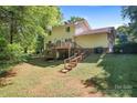 Exterior view of the back of the house with a deck, stairs, and tree-filled yard at 335 Bob White Run, Salisbury, NC 28147