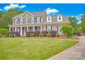 Inviting two-story home featuring a manicured lawn, brick accents, covered front porch, and mature landscaping at 3864 Meadow Ridge Nw Dr, Concord, NC 28027