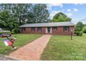 Charming brick home with a brick pathway and mailbox adorned with a North Carolina flag amid green lawns at 402 School St, Rockwell, NC 28138