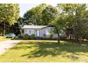 Attractive single-story home with a gray exterior, metal roof, well-kept lawn, and mature trees at 5014 Oxford School Rd, Claremont, NC 28610