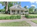 Quaint single-story home with a covered front porch, dormer window, mature trees, and lush landscaping at 531 Walnut St, Statesville, NC 28677