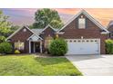 Charming brick home at sunset featuring a two-car garage and well-maintained lawn at 5706 Sustar Dr, Monroe, NC 28110