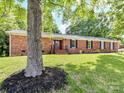 Beautifully landscaped front yard of a brick home with mature shade tree at 70 Cumberland Sw Ct, Concord, NC 28025