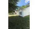 Well-maintained home showcasing white vinyl siding, a charming window with shutters, and a well-kept lawn at 8708 Goldfields Dr, Charlotte, NC 28227
