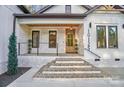 Inviting entryway with stone facade, brick steps, wood door, and modern lighting fixtures under a covered porch at 10125 Bethel Church Rd, Midland, NC 28107
