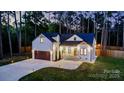 A beautifully lit home at dusk featuring board and batten siding, dark roof, and well-manicured landscape at 10125 Bethel Church Rd, Midland, NC 28107