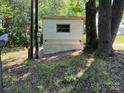 Storage shed between a telephone pole and a large tree on a grassy yard at 1029 Sullivan St, Wadesboro, NC 28170