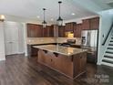 A spacious kitchen featuring a large island with granite countertops, stainless steel appliances, and dark wood cabinets at 1071 Bassett Way, Fort Mill, SC 29707