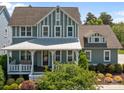 Charming two-story home with a welcoming front porch and beautifully landscaped front yard and attractive green and white color scheme at 10822 Brandie Meadow Ln, Huntersville, NC 28078
