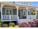 Inviting front porch with classic white railings, comfortable seating, and lush, colorful landscaping at 10822 Brandie Meadow Ln, Huntersville, NC 28078