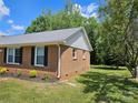Side exterior showcasing brick siding and manicured shrubbery around the house at 1109 Reid Harkey Rd, Matthews, NC 28105