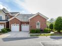 Beautiful brick home features a two-car garage, complemented by lush green bushes and manicured lawn at 140 Villa Lake Dr, Fort Mill, SC 29708