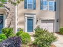 A townhome showing the entryway with blue door, garage and landscaped shrubbery at 2125 Belle Vernon Ave, Charlotte, NC 28210