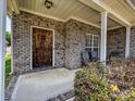 Inviting front porch featuring a decorative wood door, brick siding, and cozy seating area at 4562 Lanstone Sw Ct, Concord, NC 28027