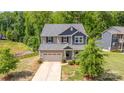 A picturesque two-story home with a manicured lawn, quaint front porch, and a two-car attached garage at 5065 Watersail Way, Clover, SC 29710