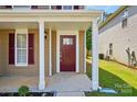 Inviting front porch featuring a brick-red door with glass accents and white columns at 6430 Matlea Ct, Charlotte, NC 28215