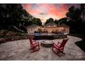 Outdoor living space with patio, fire pit, lounge chairs, pool, lush landscape, and a rock slide feature at 8305 Bar Harbor Ln, Charlotte, NC 28210