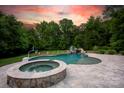 Backyard pool featuring a spa, slide with waterfall, basketball court, and lounge chairs, set against a verdant backdrop at 8305 Bar Harbor Ln, Charlotte, NC 28210