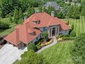 Expansive home with a red roof, surrounded by mature trees and a beautifully maintained lawn at 8904 Woodhall Lake Dr, Waxhaw, NC 28173