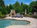 Inviting pool area with comfortable lounge seating and outdoor fireplace in a private backyard at 8904 Woodhall Lake Dr, Waxhaw, NC 28173