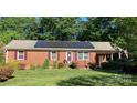 Charming brick home with purple shutters, solar panels, and a well-maintained lawn in a quiet neighborhood at 1750 Sells Rd, Salisbury, NC 28144