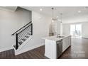 A modern kitchen island is shown with white cabinets, stainless steel appliances, and hanging lights at 2013 Clarksdale Dr # 38, Charlotte, NC 28206