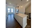 Kitchen island with stainless steel sink, white cabinets, quartz countertops, and pendant lighting at 2013 Clarksdale Dr # 38, Charlotte, NC 28206