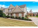 Side view of a charming two-story home with stone facade and manicured landscaping in a suburban setting at 282 Fischer Rd, Fort Mill, SC 29175