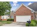 View of the brick and stone facade, and an attached two-car garage with mailboxes, and a well-manicured lawn at 2910 Lake James Ct, Monroe, NC 28110