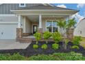 Inviting front porch with brick accents, stone columns, and rocking chairs at 4040 Deep River Way, Waxhaw, NC 28173