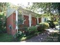 Charming brick home featuring a covered front porch with classic white pillars and mature landscaping at 5127 Murrayhill Rd, Charlotte, NC 28210