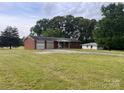 View of the brick home, two-car garage, out-building, and surrounding green lawn at 675 E Ritchie Rd, Salisbury, NC 28146