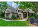 Charming brick home featuring a manicured lawn, mature trees, and elegant landscaping at 7138 Wessynton Dr, Charlotte, NC 28226