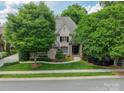 Charming brick home featuring a manicured lawn, mature trees, and elegant landscaping at 7138 Wessynton Dr, Charlotte, NC 28226