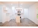 A bright, modern kitchen with stainless steel appliances, white cabinets, an island with sink and wood-look floors at Lot 1 New Pineola Rd, Charlotte, NC 28208