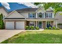 Beautiful two-story home with a stone facade, covered porch, and lush landscaping in a Gathering-friendly neighborhood at 136 Elba Dr, Mooresville, NC 28115