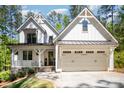 Beautiful two-story farmhouse with white siding, black trim, and a welcoming front porch and attached garage at 16432 Here At Last Ln, Charlotte, NC 28278