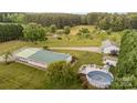 Aerial view showcasing the home, detached garage, and backyard above-ground pool with decking, set amidst mature trees at 1720 Lowe Dr, Catawba, NC 28609